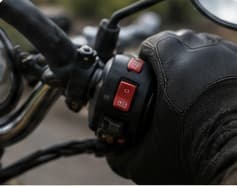 A gloved hand on the handlebar switchgear